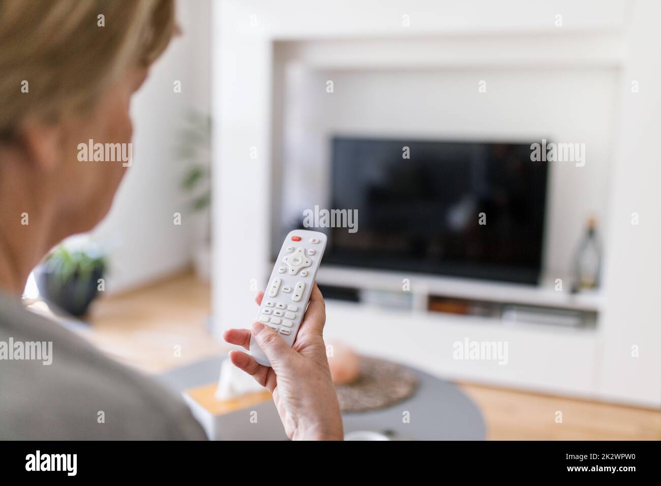 Donna anziana con telecomando per guardare la tv Foto Stock