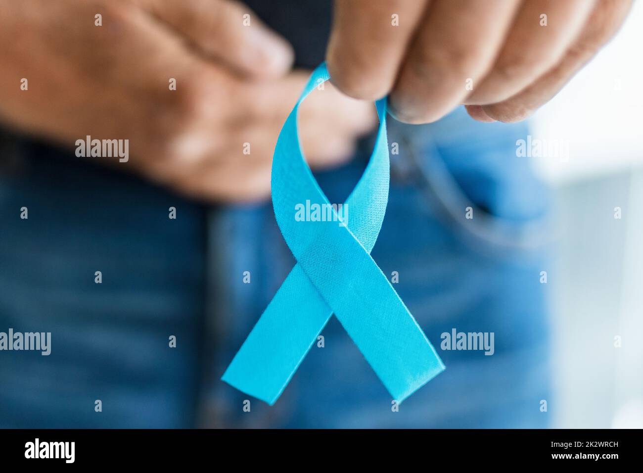 Uomo anziano che tiene un nastro blu di consapevolezza del cancro Foto Stock