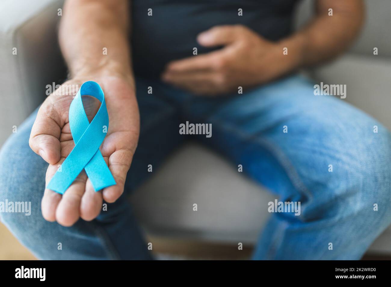 Uomo anziano che tiene un nastro blu di consapevolezza del cancro Foto Stock