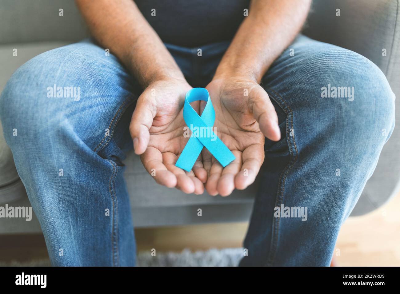 Uomo anziano che tiene un nastro blu di consapevolezza del cancro Foto Stock