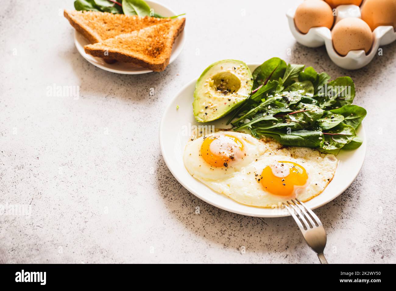 Colazione salutare con pane tostato integrale, uova con insalata verde, avocado. Colazione tradizionale Foto Stock