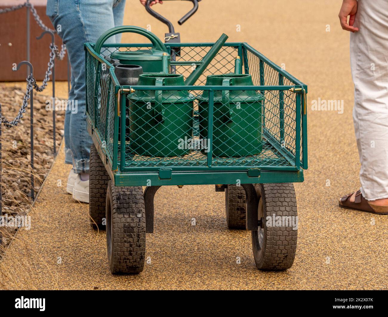 Tiri lungo il carrello caricato in su con le lattine di innaffiamento in un divieto britannico del tubo flessibile di siccità. Foto Stock