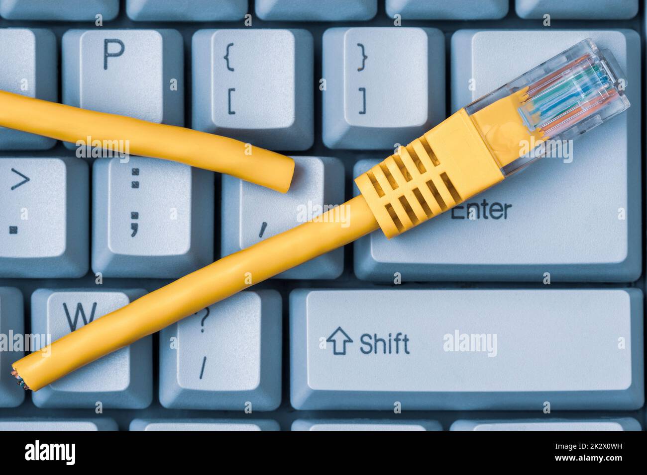 Tastiera blu del computer con cavo di rete giallo tagliato Foto Stock