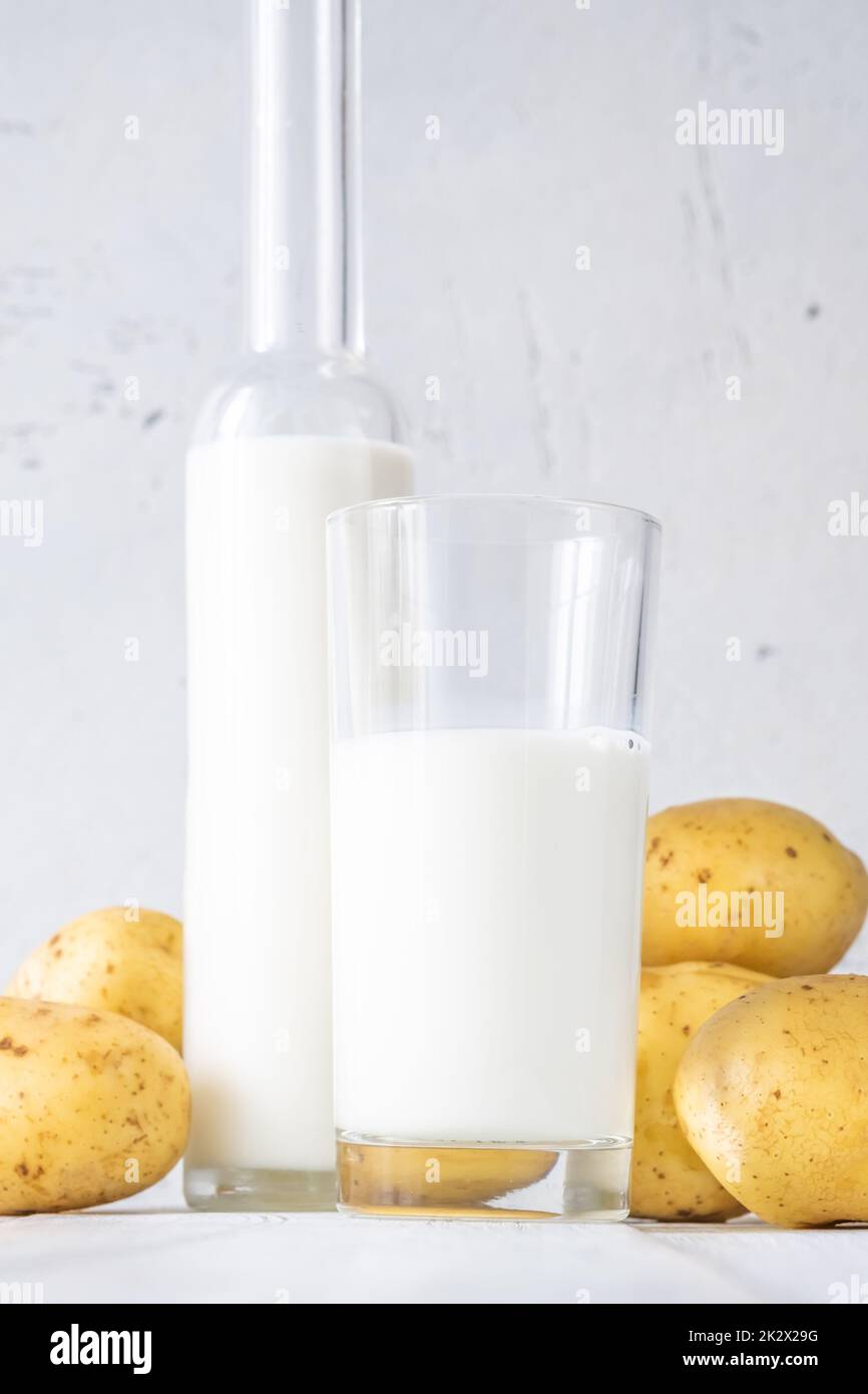 Bottiglia di vetro di latte di patate con patate Foto Stock