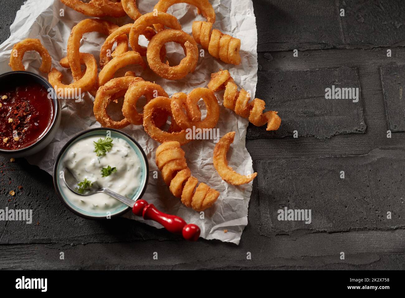 Anelli di cipolla fritti e patatine fritte arricciate Foto Stock