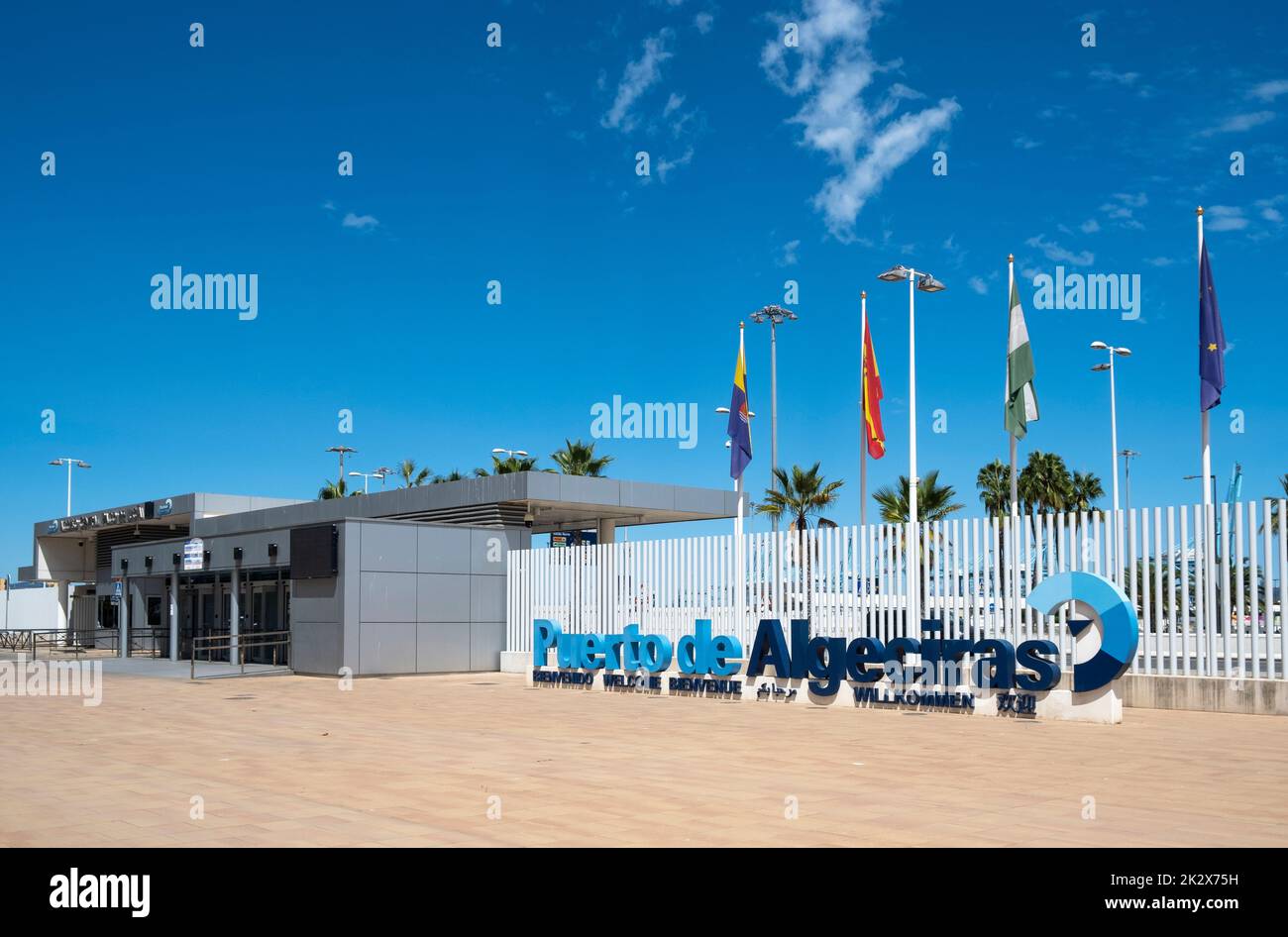 Il cartello con il logo Puerto de Algeciras (Porto di Algeciras) con le bandiere dietro, che si trova vicino all'ingresso principale dei passeggeri. Foto Stock