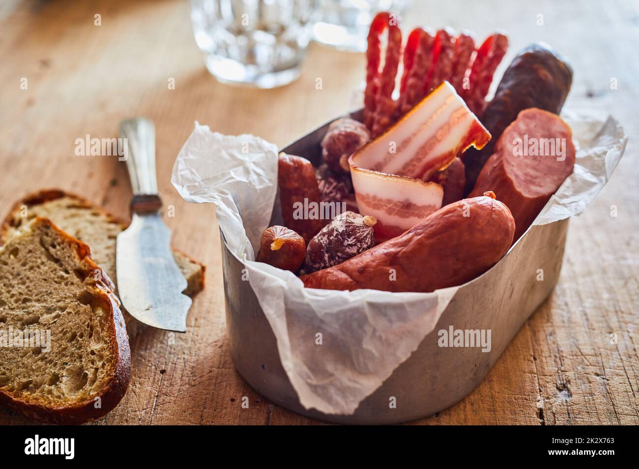 Salsicce assortite sul tavolo con pane Foto Stock