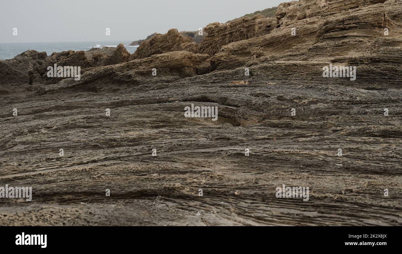 Solette di roccia volcanogene sulla riva del mare. Frangiflutti rocciosi naturali in riva al mare Foto Stock