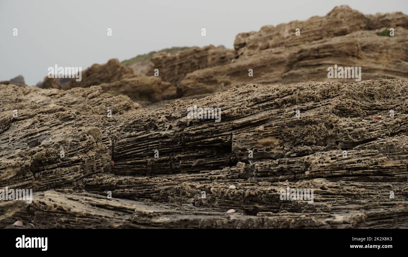 Solette di roccia volcanogene sulla riva del mare. Frangiflutti rocciosi naturali in riva al mare Foto Stock