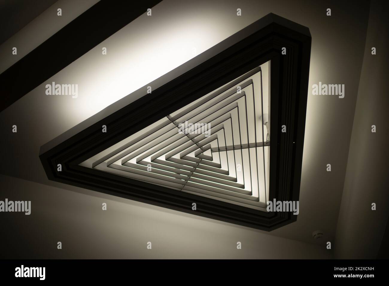 Sorgente luminosa triangolare. Luce nell'abitacolo. Luce di design. Dettagli dell'architettura. Foto Stock
