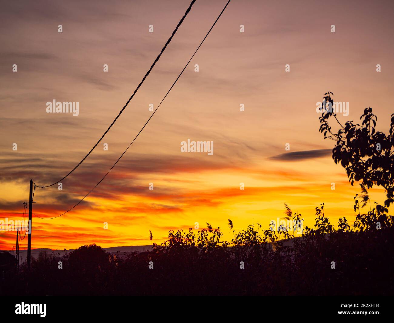 Un tramonto colorato vicino alla linea elettrica che scorre Foto Stock