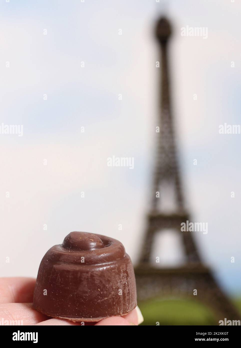 Tartufi francesi al cioccolato in mano con la sfocata Torre Eiffel sullo sfondo Foto Stock