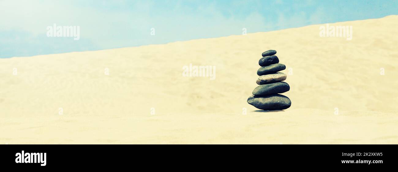 Pietre equilibrato su una spiaggia di ciottoli durante il tramonto. Foto Stock