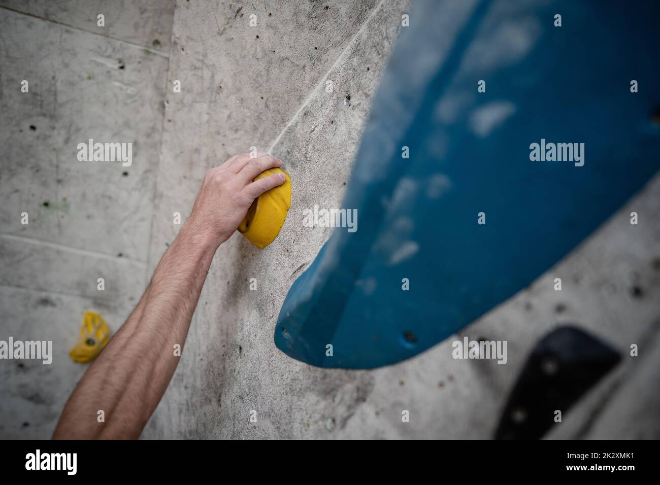 Mani maschili cosparse di polvere di magnesio che afferra una presa di una parete da arrampicata Foto Stock
