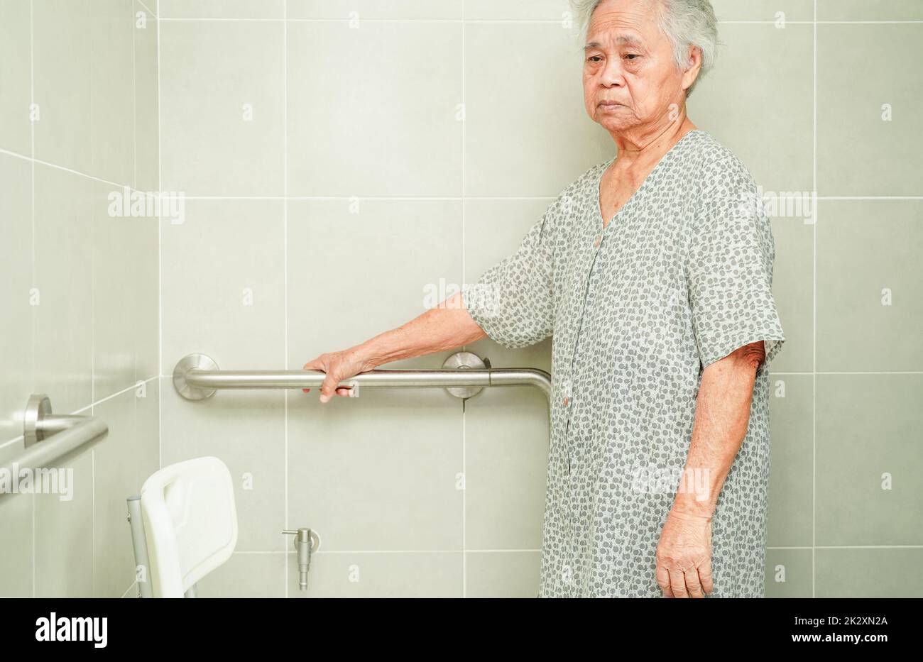 Anziana asiatica paziente donna uso servizi igienici sostegno in bagno, corrimano di sicurezza barra di presa, sicurezza in ospedale di cura. Foto Stock