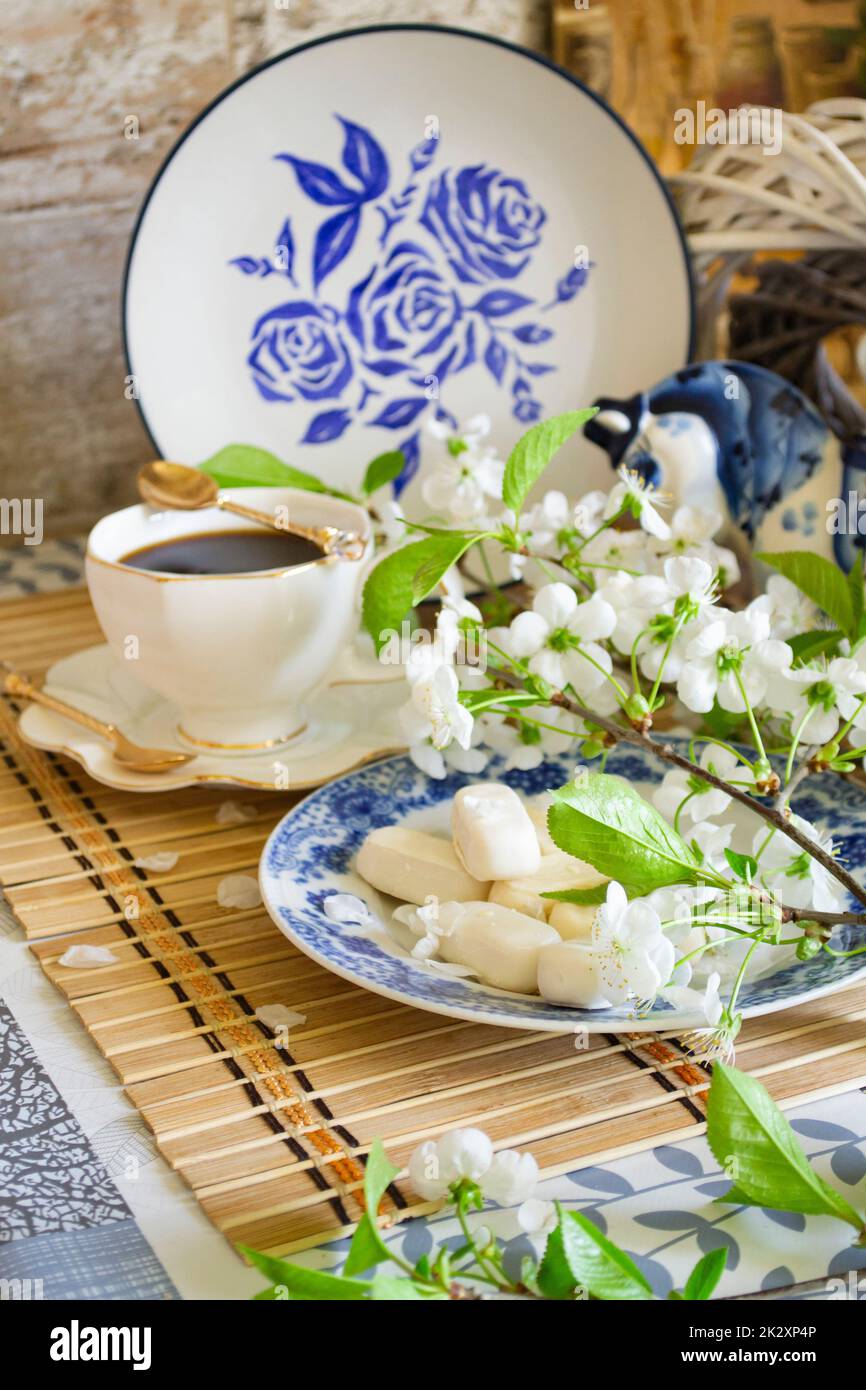 Relax mattutino, piatti per la colazione e elementi decorativi dipinti nello stile di Gzhel, tè, caffè e fiori bianchi di ciliegia Foto Stock