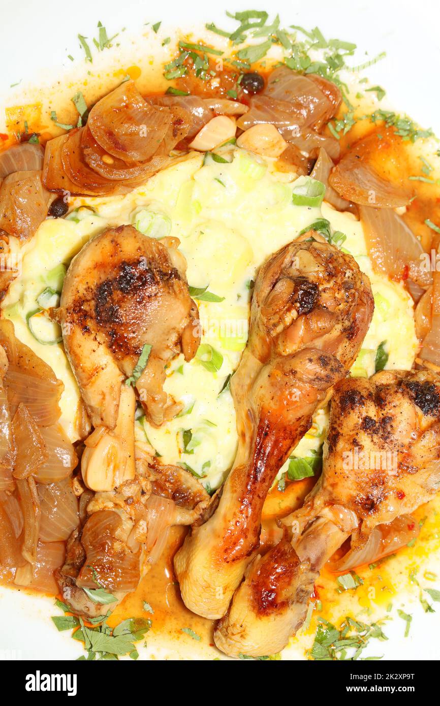 Cosce di pollo primo piano brasate con cipolle di macellaio servite con purè di patate alle erbe cucina greca moderne stampe di alta qualità Foto Stock