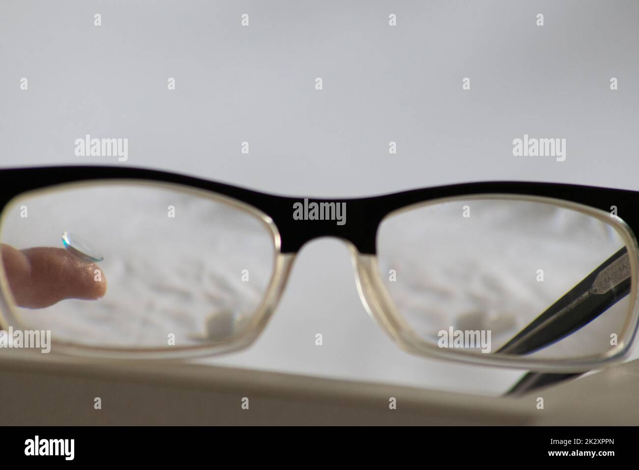 La lente a contatto blu attraverso gli occhiali neri mostra occhiali diversi per correggere la lungimiranza e la prossimità tramite optometria o medico oculare contro la miopia con correzione visiva degli occhi per una visione perfetta Foto Stock