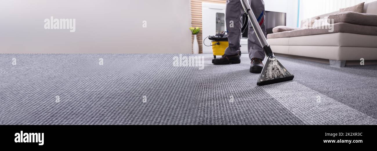 Persona Pulizia tappeto con un aspirapolvere Foto Stock