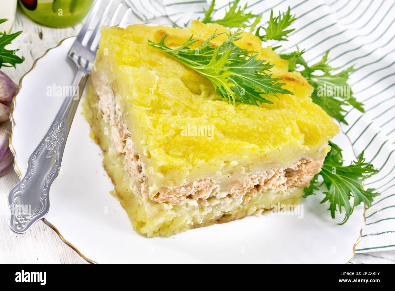 Casseruola con patate e pesce in piatto su tavola di legno chiaro Foto Stock