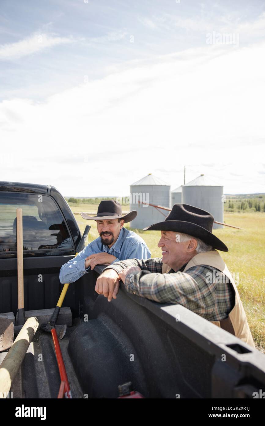 Padre e figlio contadini che parlano a pick-up camion in soleggiata fattoria rurale Foto Stock