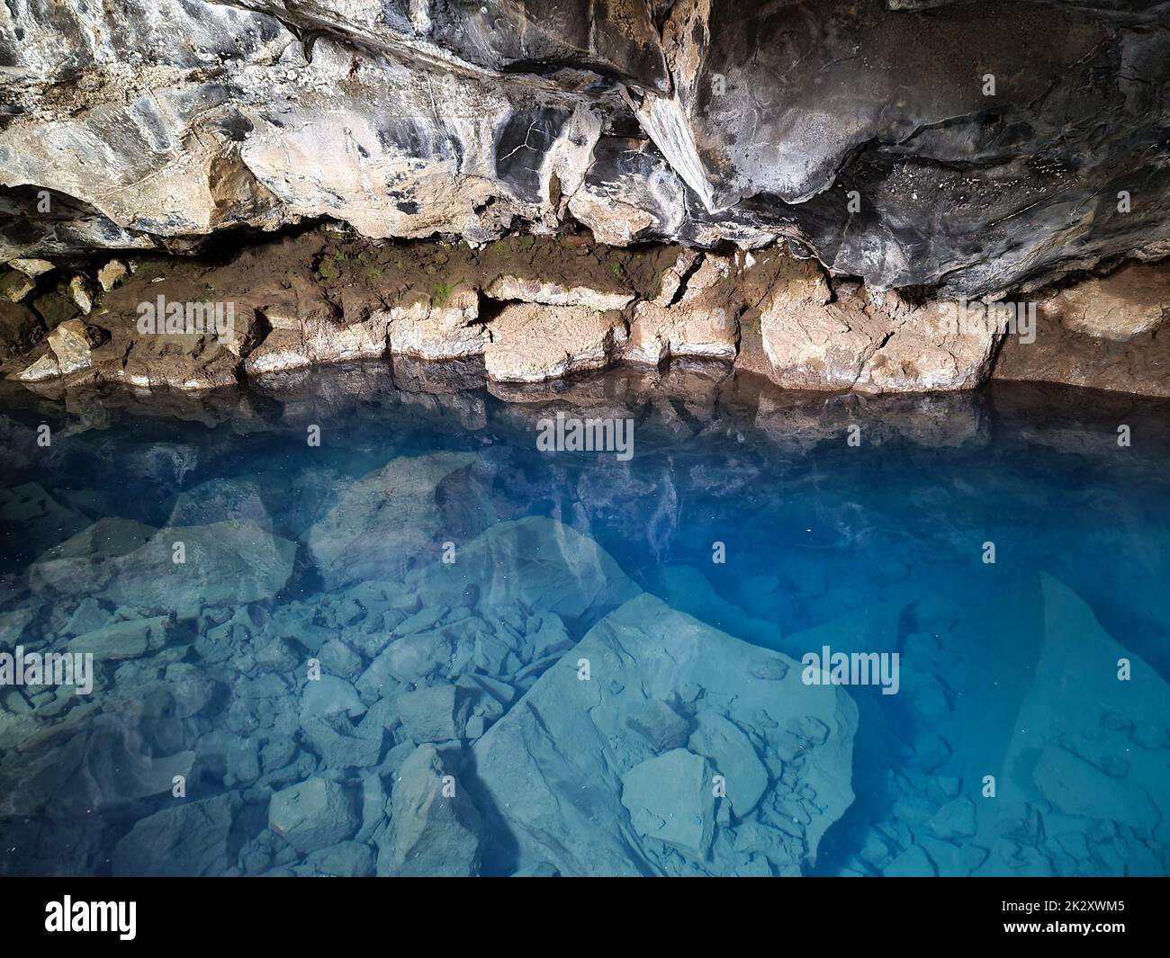 Ammira la grotta lavica di Grjotagja con acqua blu cristallina. Foto Stock