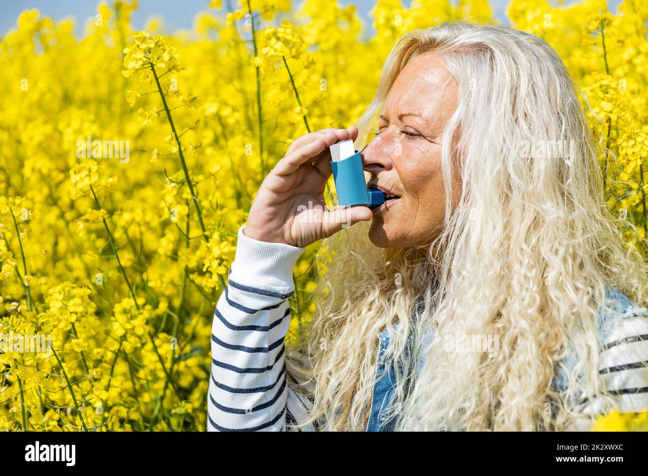 Donna con inalatore avente attacchi di asma sulla giornata di primavera Foto Stock