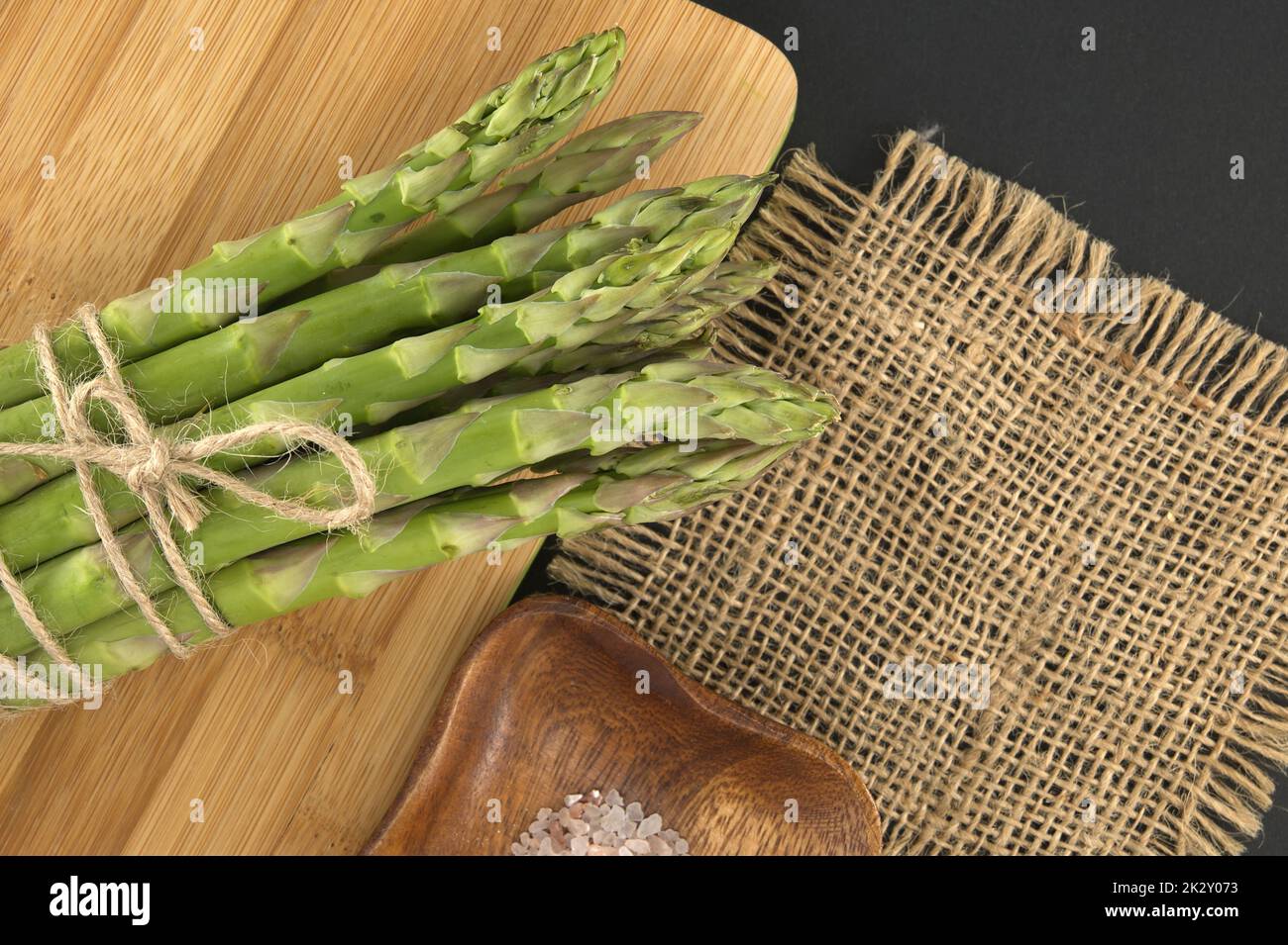 Asparagi verdi sul tagliere su sfondo nero Foto Stock