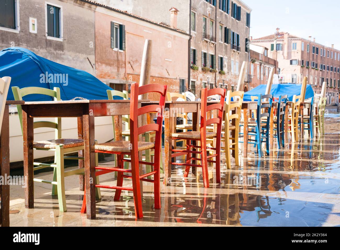 Sedie colorate in fila lungo il canale veneziano Foto Stock