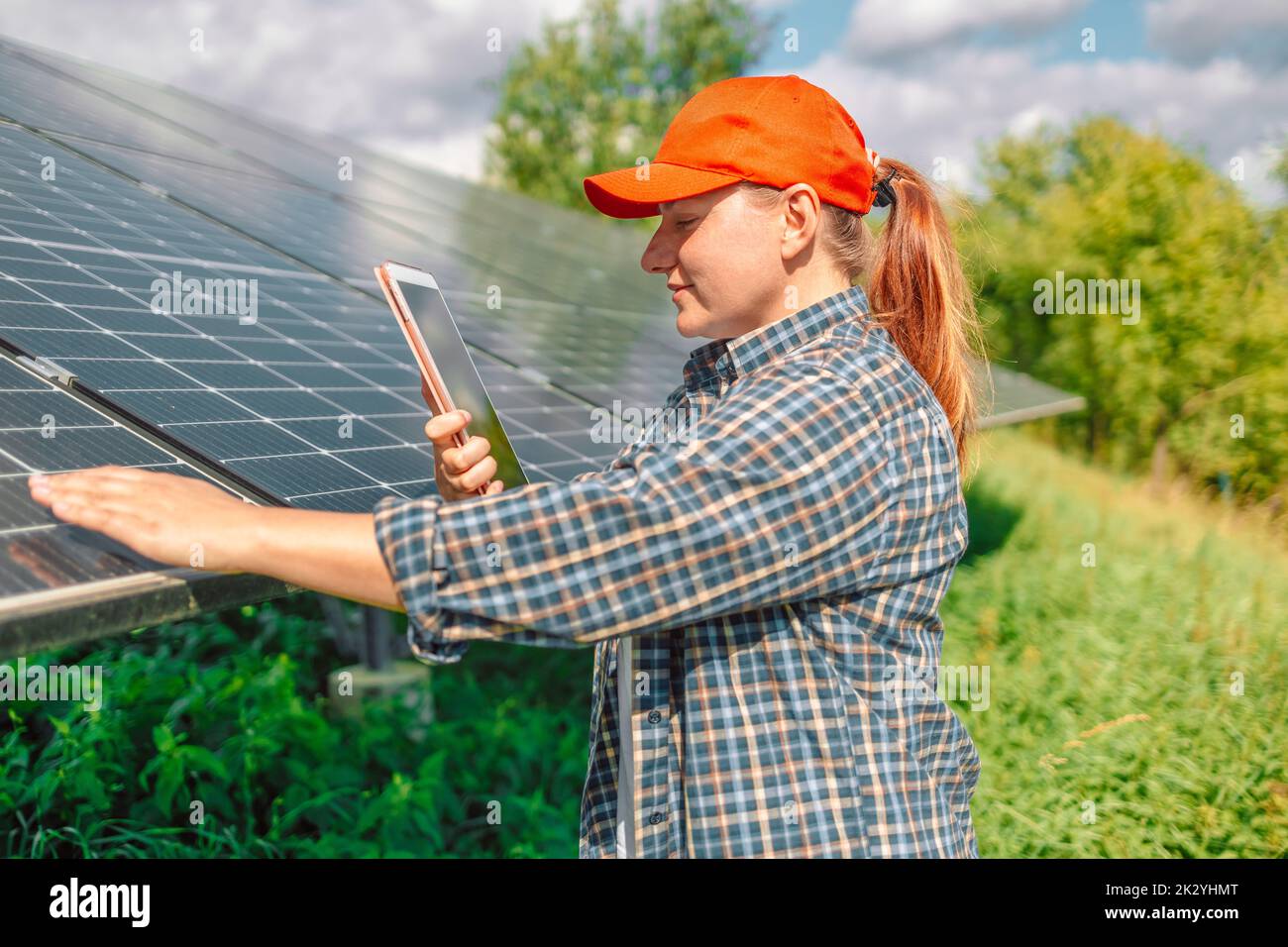 Persona che controlla la generazione di energia solare di pannelli solari per l'installazione domestica in un'app per smartphone. Foto Stock