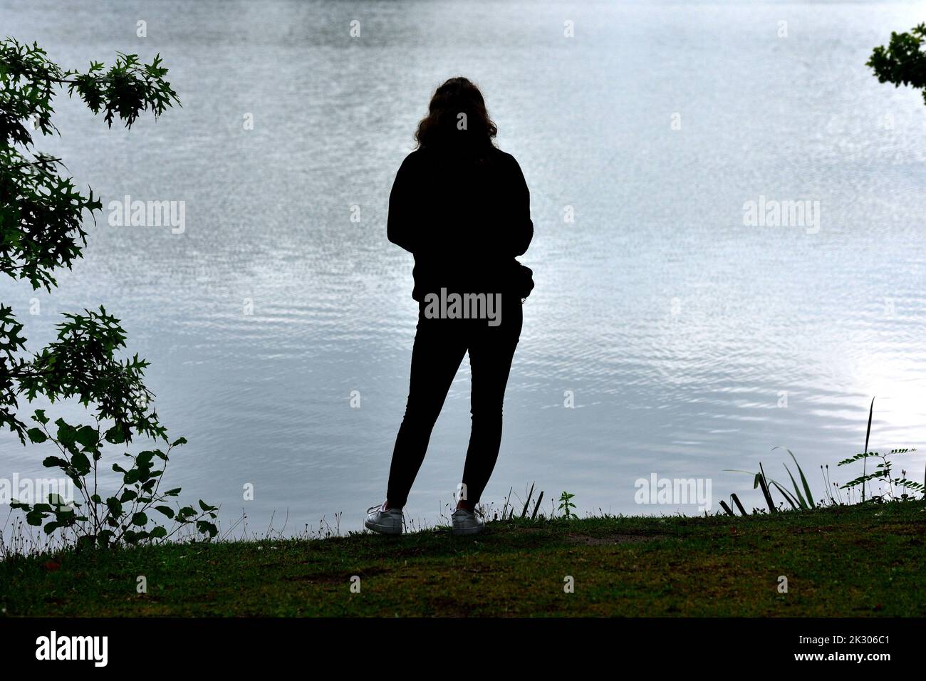 Giovane donna da dietro sulla riva di un lago Foto Stock