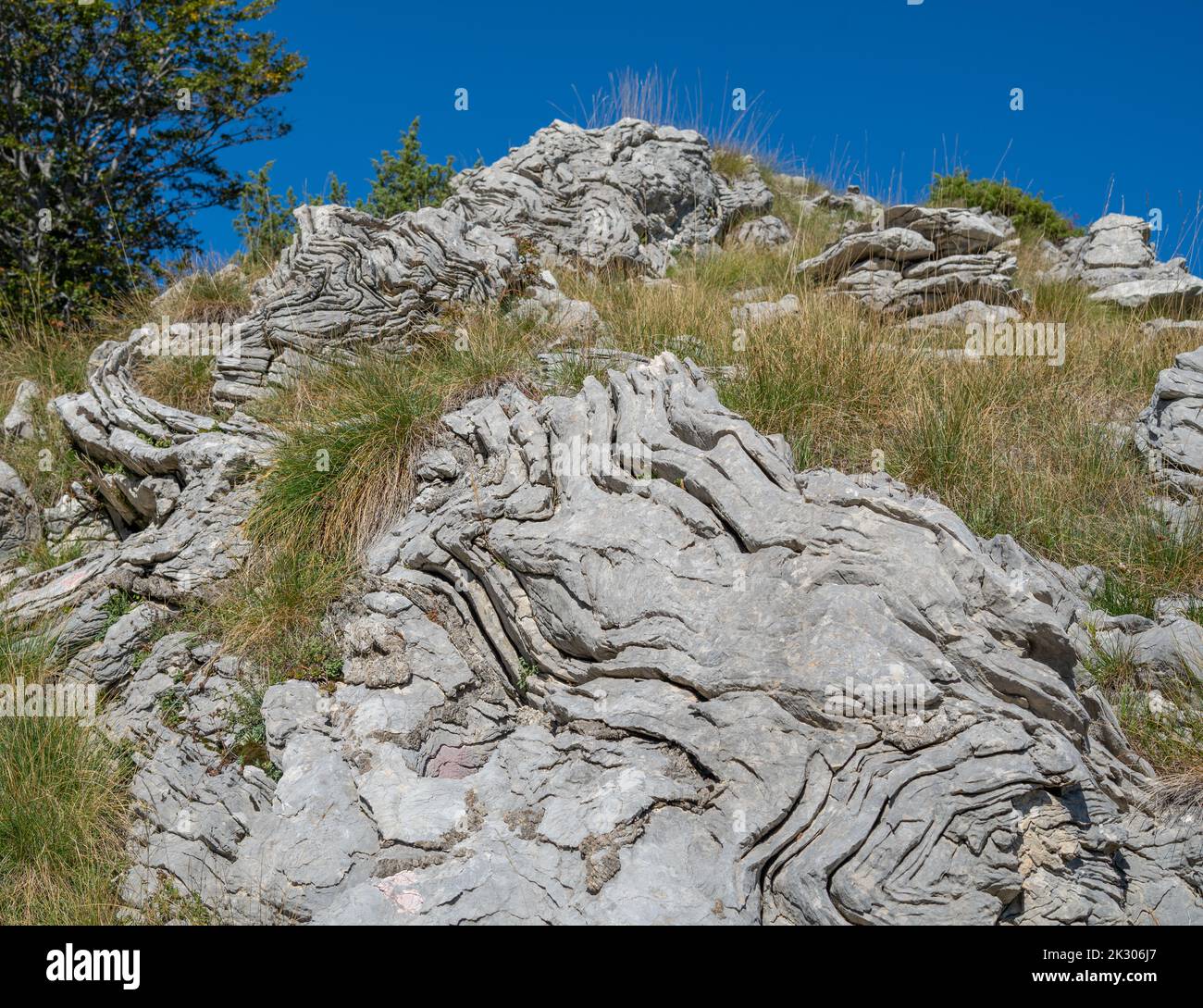 Una strana configurazione rocciosa ondulata su una montagna circondata da erba Foto Stock