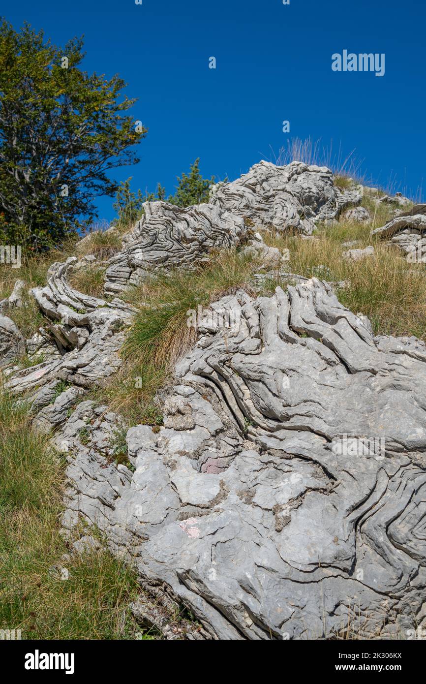 Una strana configurazione rocciosa ondulata su una montagna circondata da erba Foto Stock