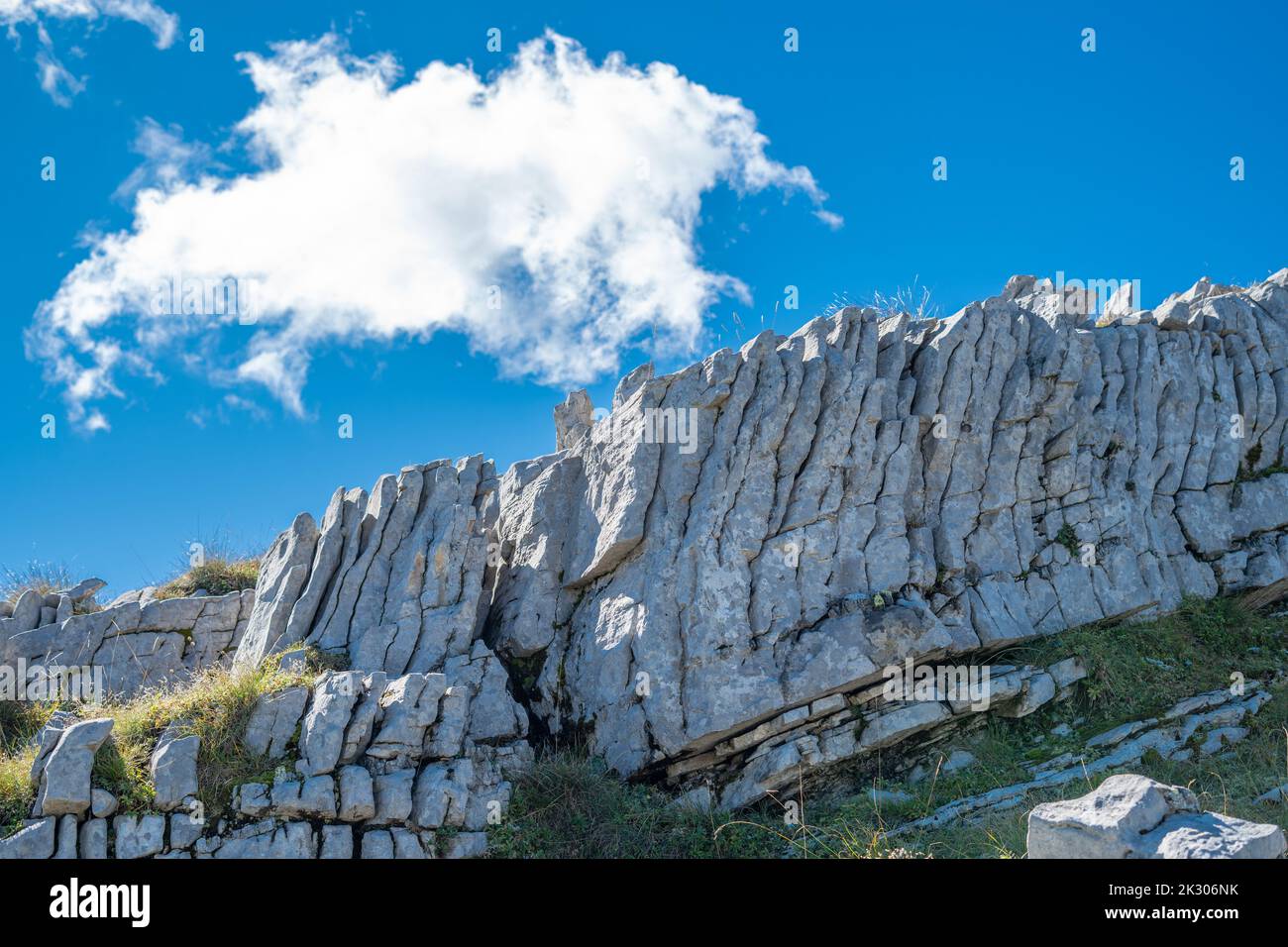 Una strana configurazione rocciosa ondulata su una montagna circondata da erba Foto Stock