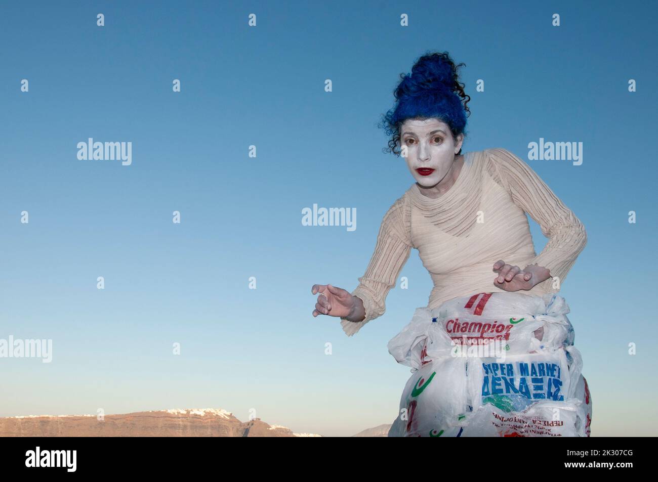 Una donna divertente mima contro il cielo blu durante una performance sull'isola di Santorini in Grecia Foto Stock