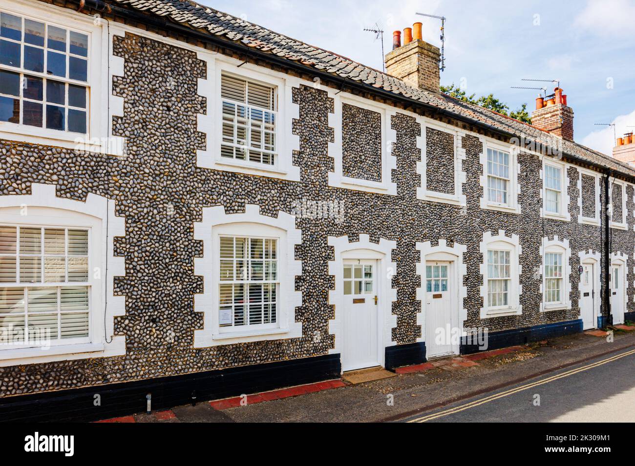 Terrazza di case di stile architettonico locale con pareti in pietra selce a Holt, una piccola città storica mercato georgiano nel nord Norfolk, Inghilterra Foto Stock