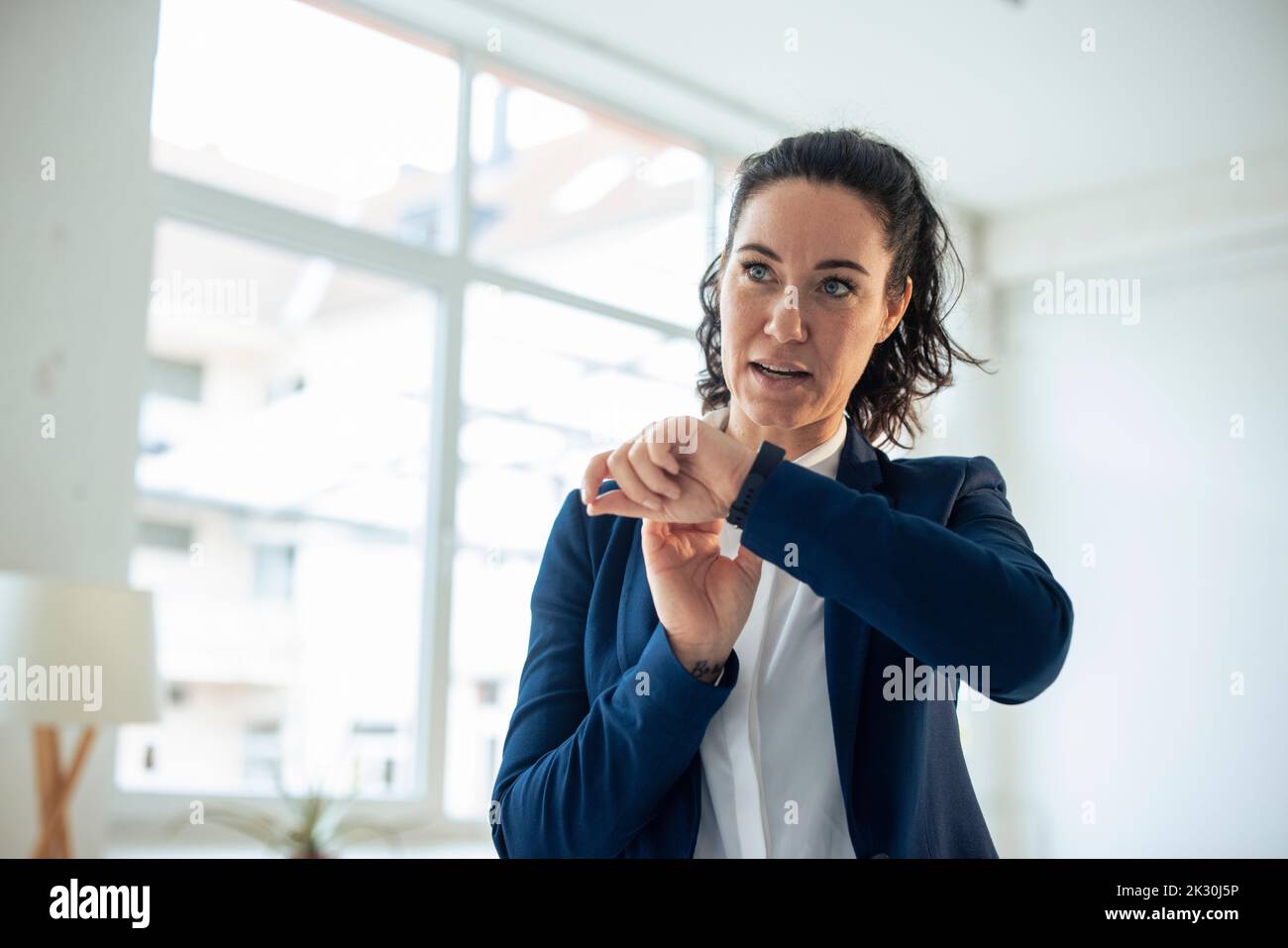 Donna d'affari che invia messaggi vocali tramite Smart Watch Foto Stock