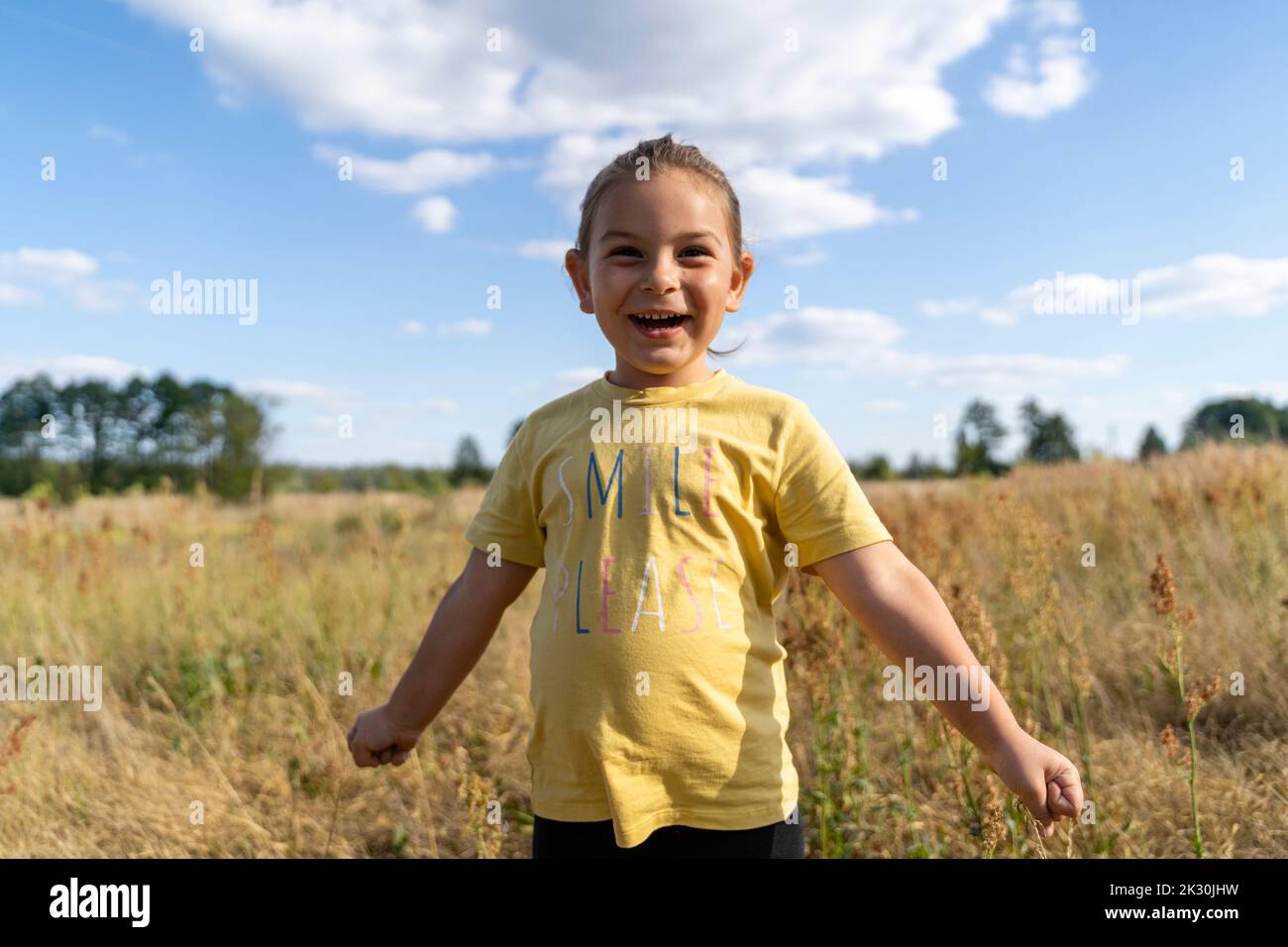 Ragazza allegra con pugno chiuso in piedi sul campo Foto Stock