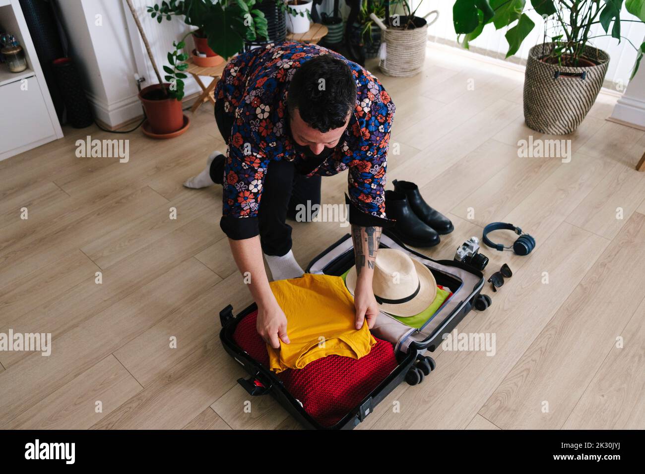 Uomo che porta i vestiti in valigia a casa Foto Stock