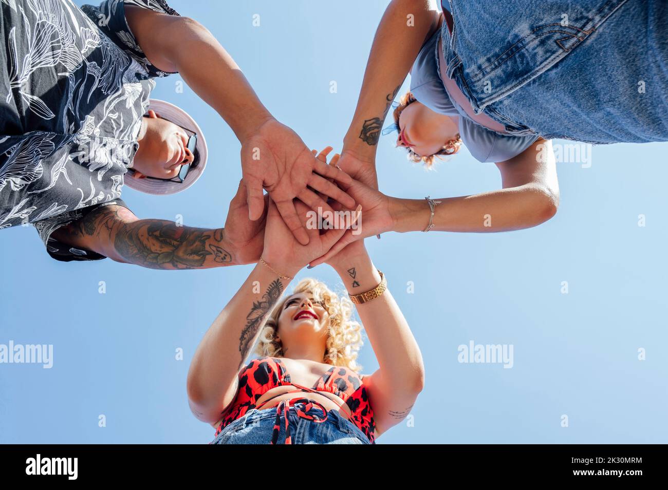 Amici con mani impilate sotto il cielo Foto Stock