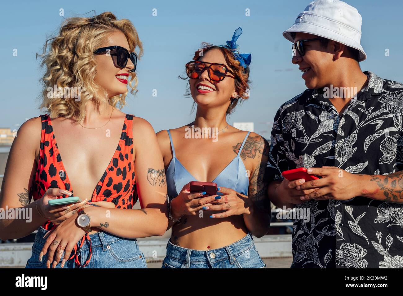 Uomo e donna con telefoni cellulari in piedi insieme nelle giornate di sole Foto Stock