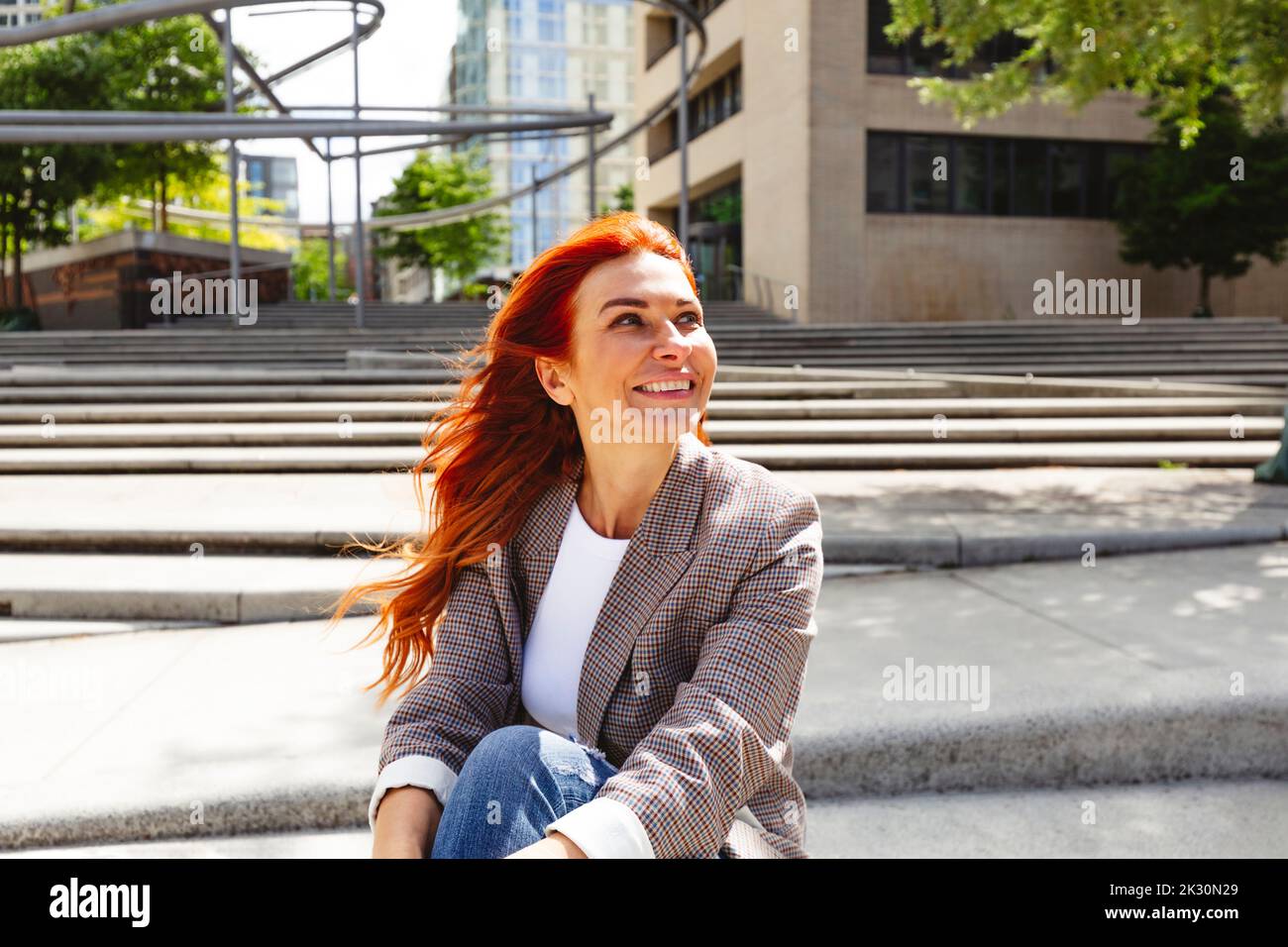 Donna sorridente arrossata seduta sui gradini Foto Stock