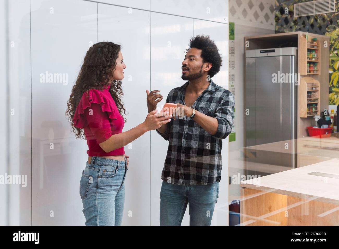 Uomo d'affari che discute sullo smartphone con un collega in caffetteria Foto Stock