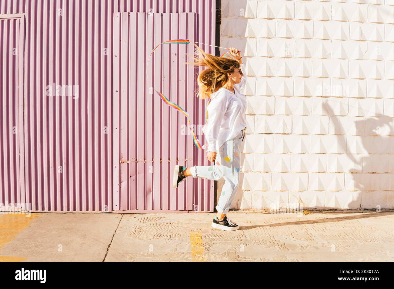 Donna che fa ginnastica ritmica di fronte al muro corrugato il giorno di sole Foto Stock