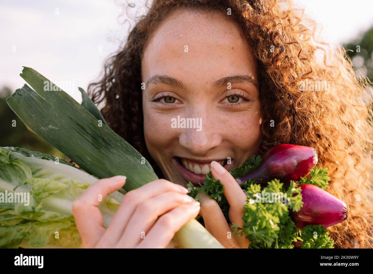 Donna sorridente che tiene verdure fresche biologiche Foto Stock