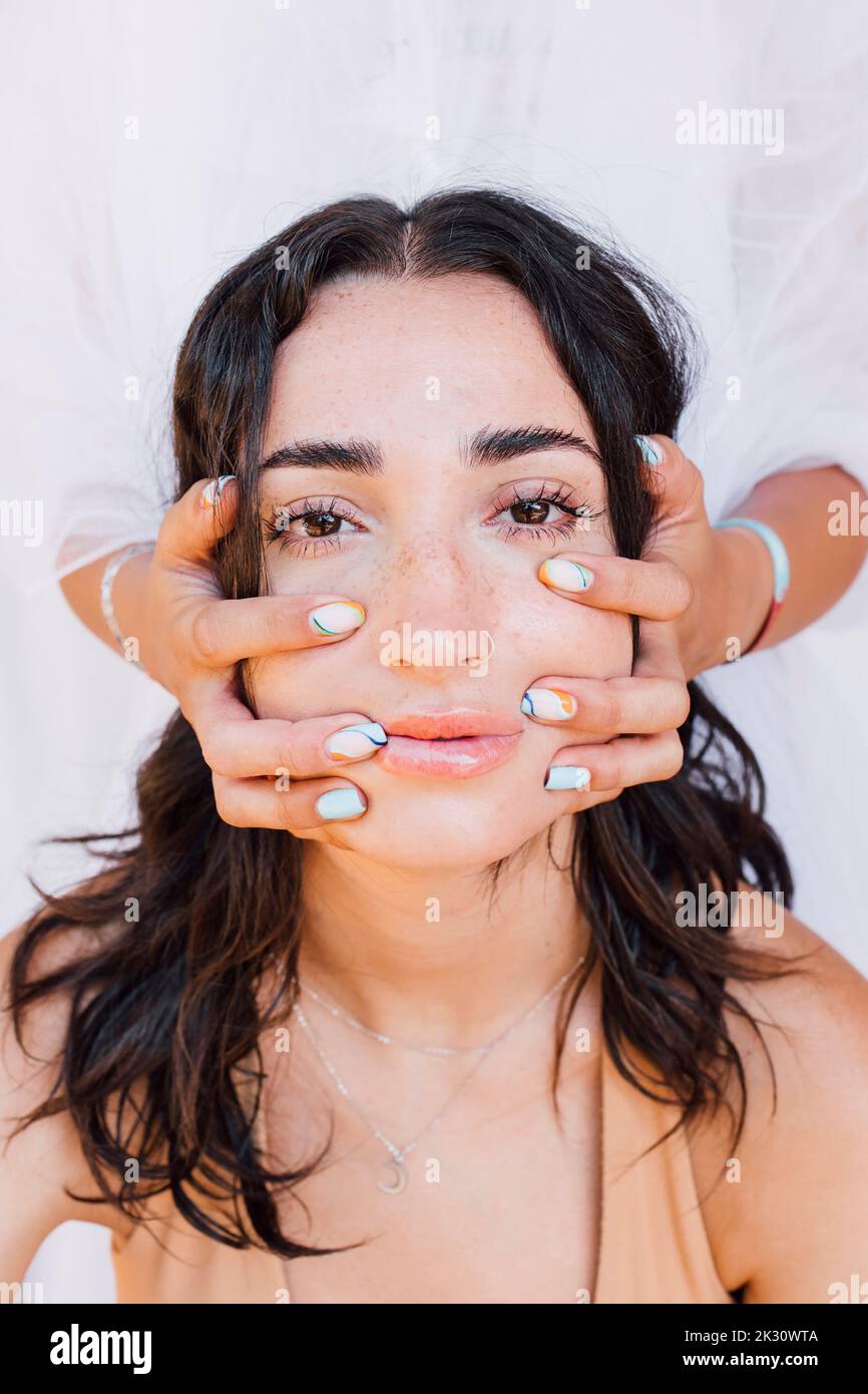 Le mani massaggiano il viso della giovane donna Foto Stock