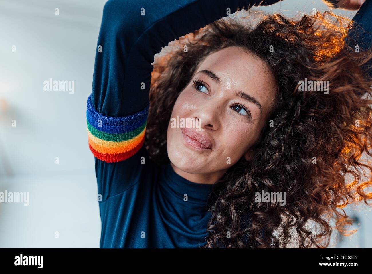 Donna sorridente con capelli ricci che indossa una fascia arcobaleno Foto Stock