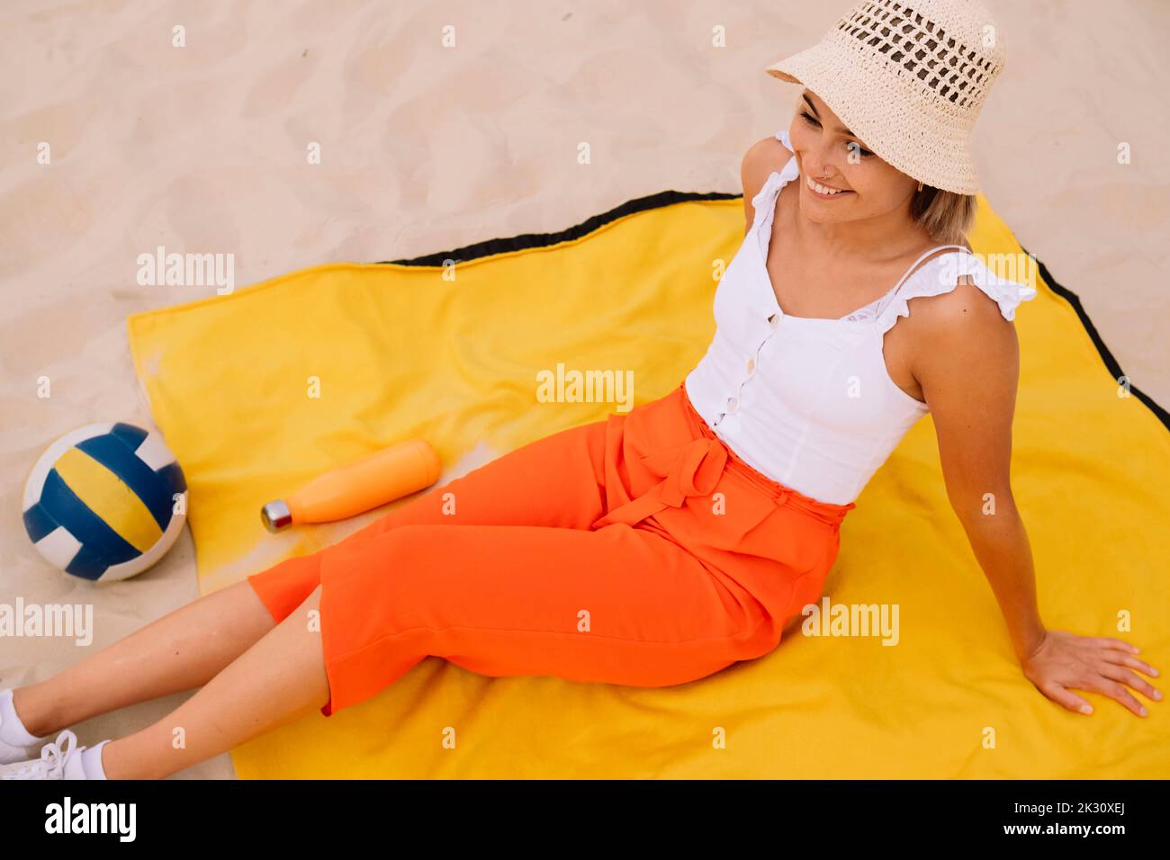 Felice giovane donna seduta nella sabbia Foto Stock