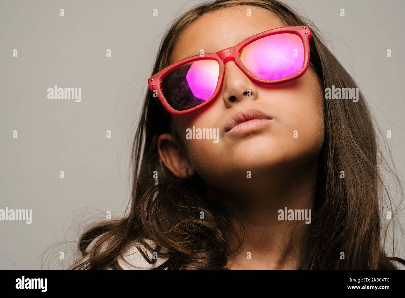 Ragazza sicura che indossa occhiali da sole su sfondo grigio Foto Stock