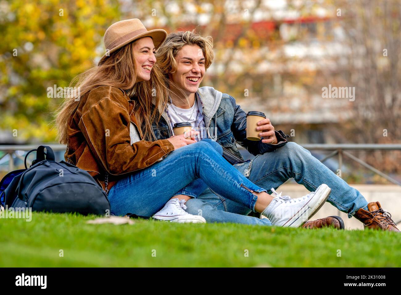 Turisti felici con tazze usa e getta seduti nel parco Foto Stock